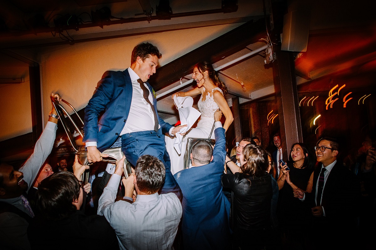 man falling off chair while dancing the hora