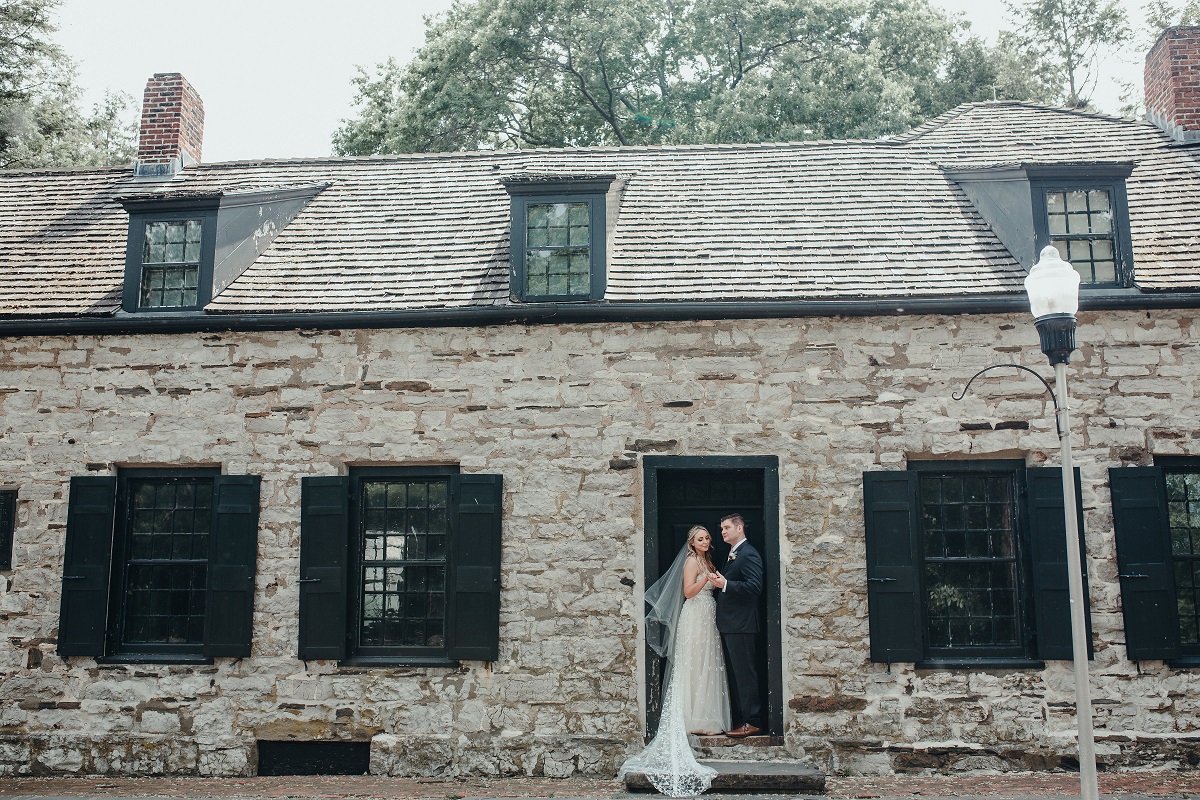bride and groom standing in a doorway, facing outside into the historic grounds of the Senate Garage